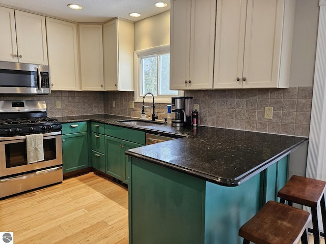 kitchen featuring appliances with stainless steel finishes, sink, a kitchen bar, and kitchen peninsula