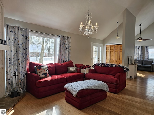 living room featuring an inviting chandelier, wood-type flooring, and high vaulted ceiling