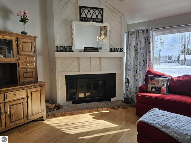 living room featuring lofted ceiling, a fireplace, and light wood-type flooring