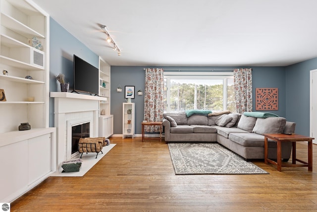 living room with track lighting, built in features, and light wood-type flooring