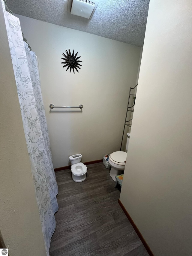 bathroom with hardwood / wood-style floors, a textured ceiling, and toilet