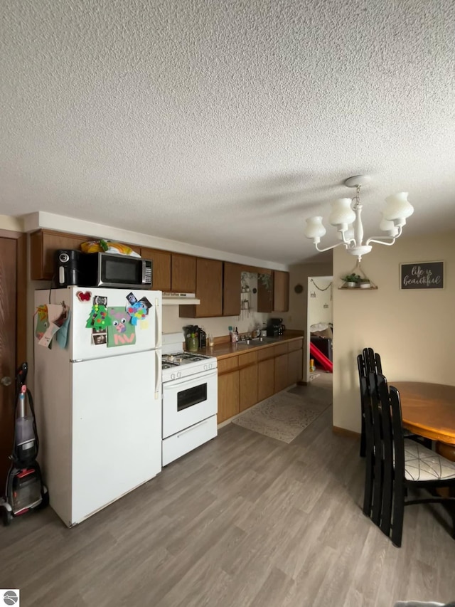 kitchen featuring white appliances, a textured ceiling, and light wood-type flooring