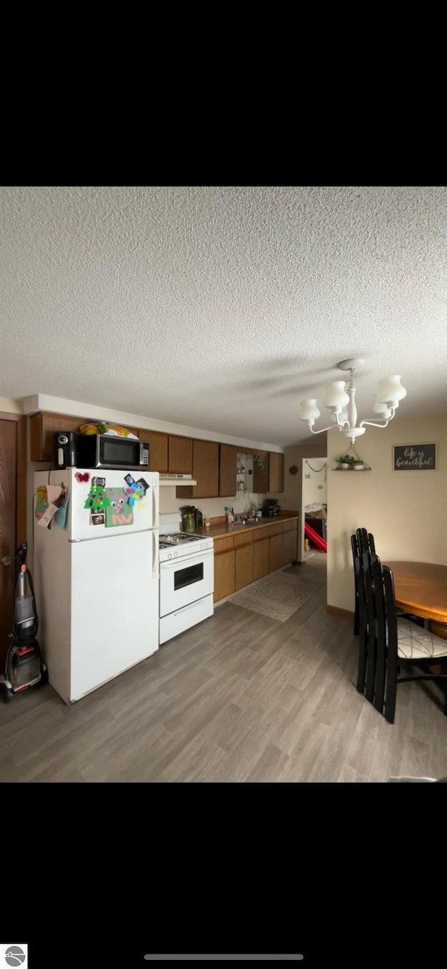 kitchen featuring a textured ceiling, white appliances, and light hardwood / wood-style flooring