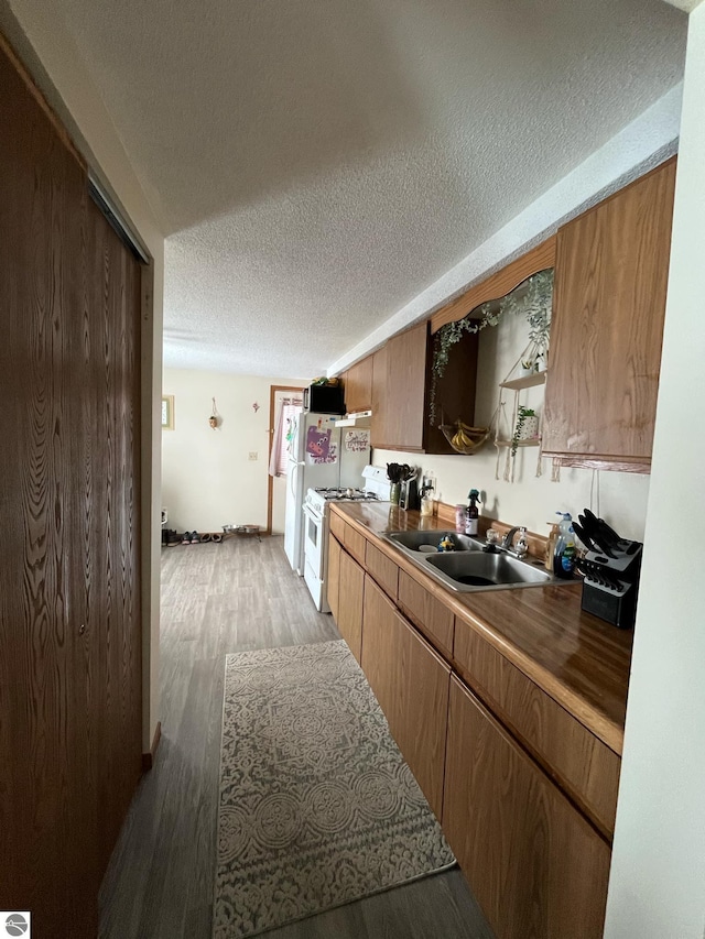 kitchen with light hardwood / wood-style floors, sink, gas range gas stove, and a textured ceiling