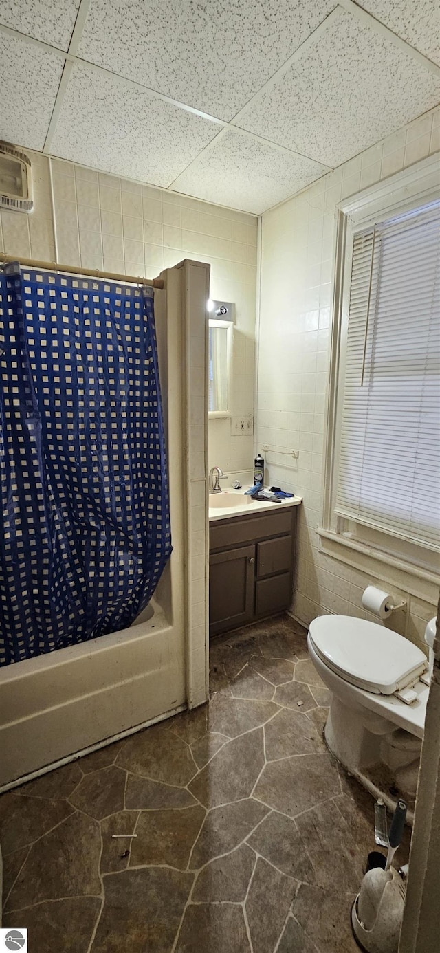 full bathroom with shower / bath combo, a paneled ceiling, vanity, and toilet