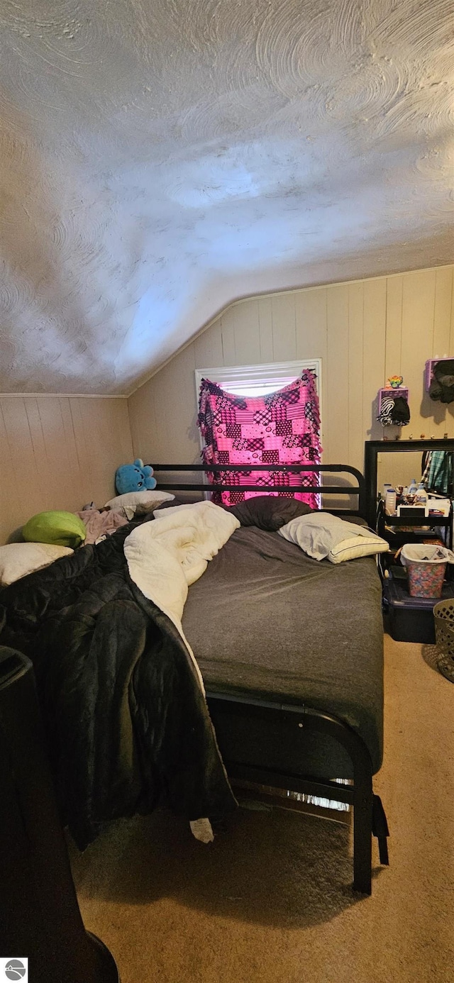 bedroom with carpet floors, vaulted ceiling, and a textured ceiling