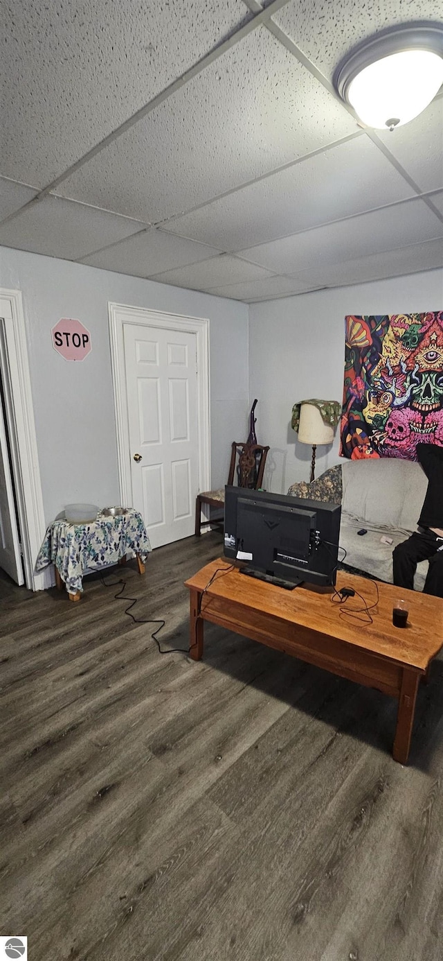 living room with dark wood-type flooring and a paneled ceiling