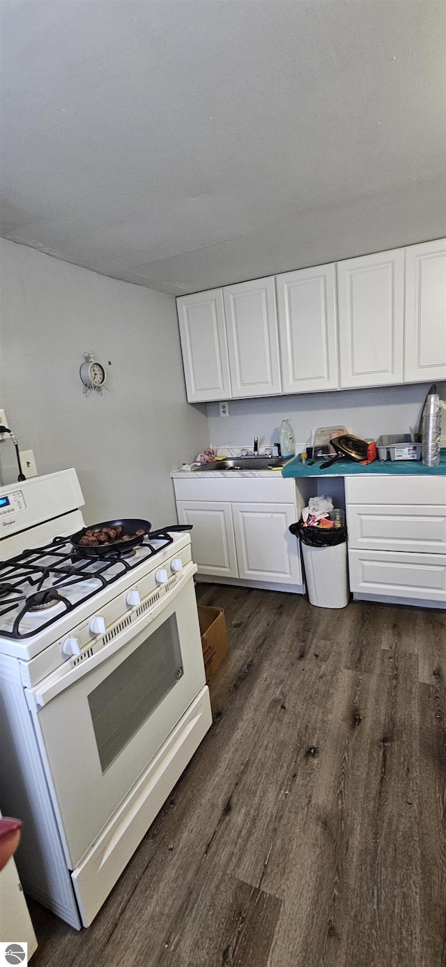 kitchen with dark hardwood / wood-style floors, white range with gas cooktop, sink, and white cabinets