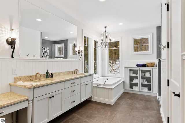 bathroom with a notable chandelier, vanity, and a tub