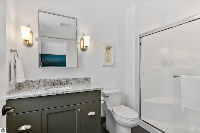 bathroom featuring an enclosed shower, vanity, and toilet