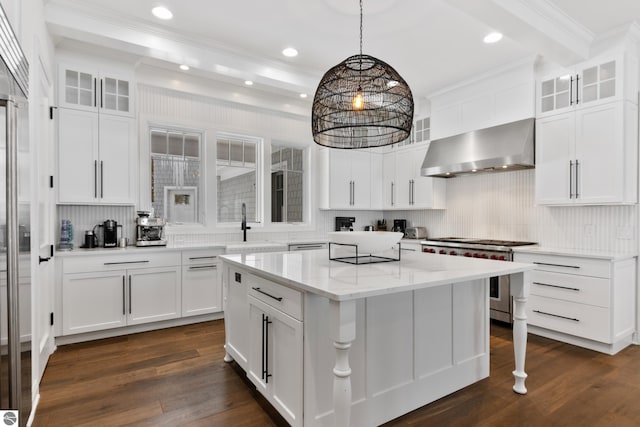 kitchen featuring white cabinetry, a center island, decorative light fixtures, high end stainless steel range oven, and wall chimney exhaust hood