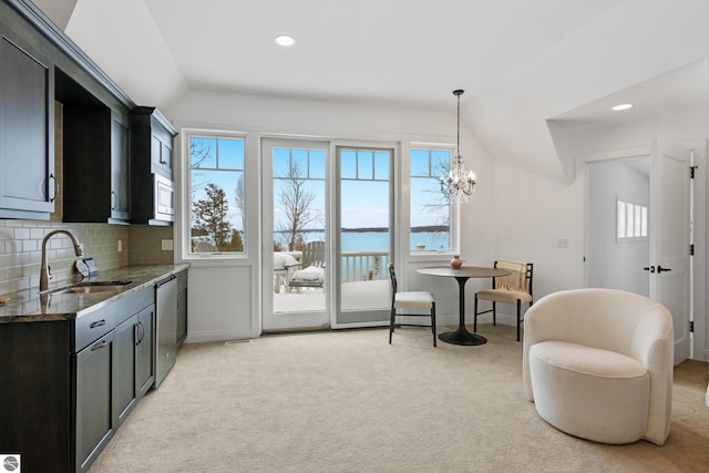 interior space with dark stone countertops, appliances with stainless steel finishes, sink, a water view, and hanging light fixtures