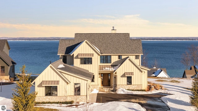 modern farmhouse with stone siding, board and batten siding, and roof with shingles