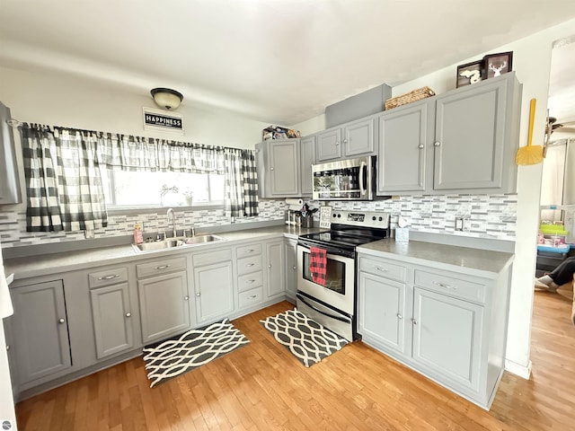 kitchen with gray cabinetry, sink, stainless steel appliances, and light hardwood / wood-style floors