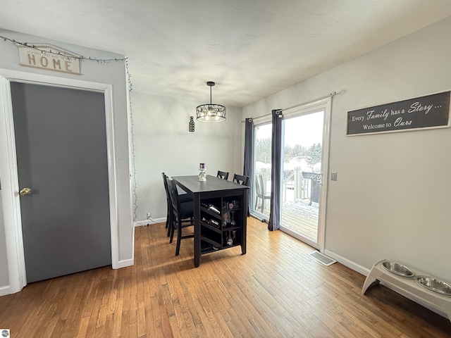 dining room featuring wood-type flooring and an inviting chandelier