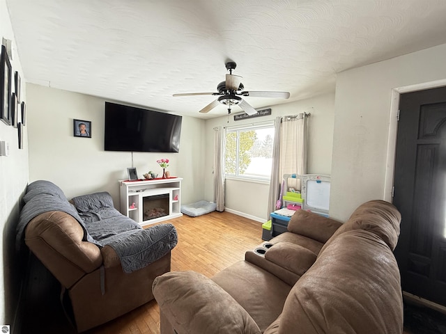 living room with hardwood / wood-style flooring, ceiling fan, and a textured ceiling