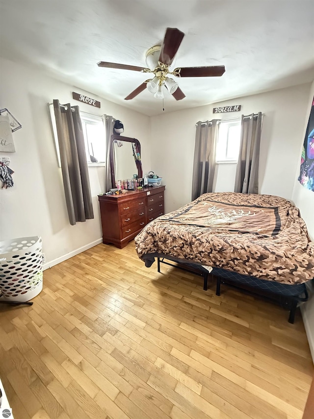 bedroom featuring ceiling fan, multiple windows, and light hardwood / wood-style flooring