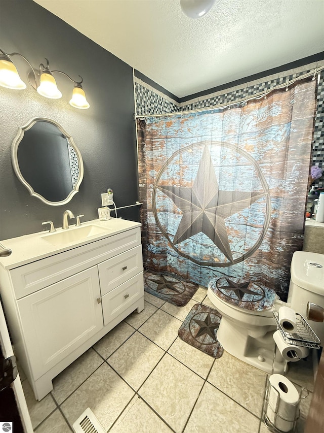 bathroom featuring tile patterned flooring, vanity, walk in shower, toilet, and a textured ceiling