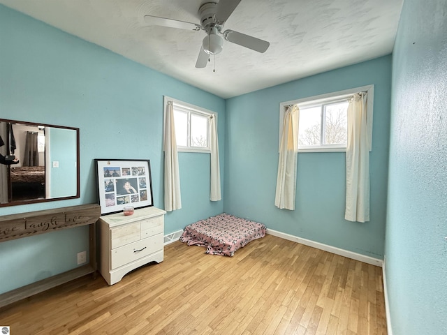 unfurnished bedroom featuring multiple windows, light hardwood / wood-style floors, and ceiling fan