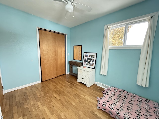 unfurnished bedroom featuring ceiling fan, light hardwood / wood-style floors, and a closet