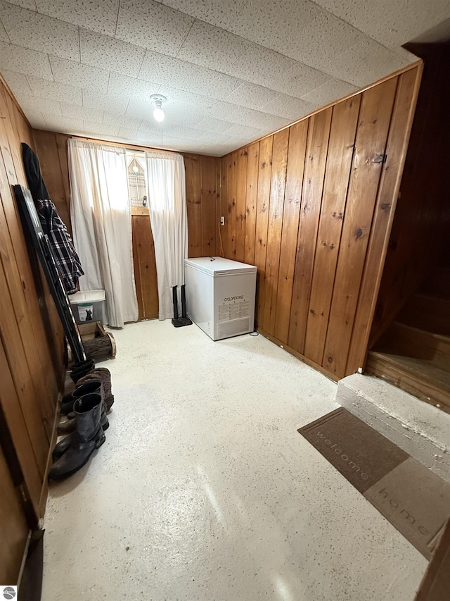 interior space with a drop ceiling and wood walls