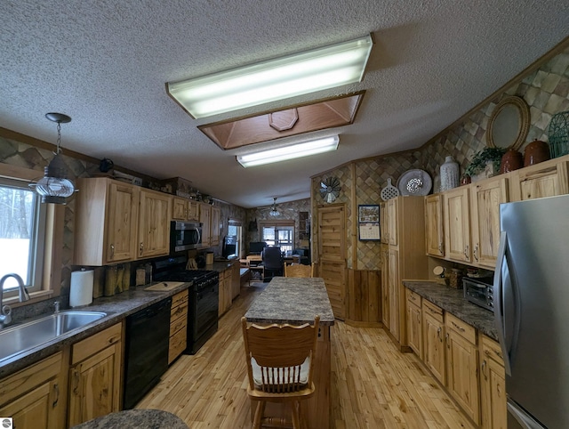 kitchen with lofted ceiling, sink, light wood-type flooring, pendant lighting, and black appliances