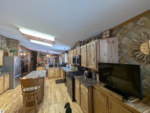 kitchen featuring lofted ceiling, sink, light hardwood / wood-style flooring, stainless steel appliances, and decorative light fixtures