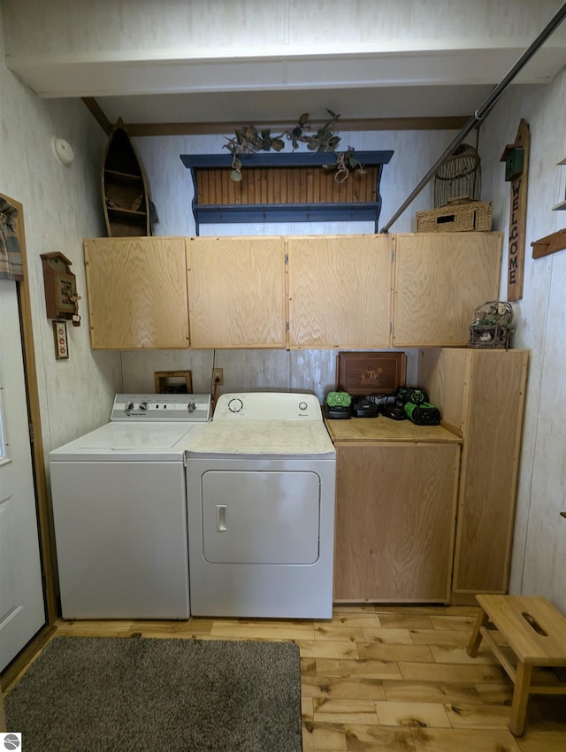 washroom featuring cabinets, washer and clothes dryer, and light hardwood / wood-style flooring