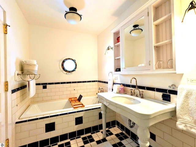 bathroom featuring a relaxing tiled tub, sink, and tile patterned flooring