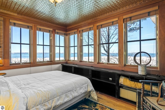 bedroom featuring an ornate ceiling, wood finished floors, a water view, and multiple windows