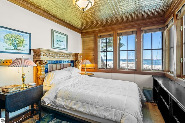 bedroom featuring an ornate ceiling, wood finished floors, and crown molding