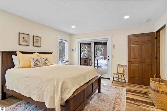 bedroom with light hardwood / wood-style flooring, access to outside, and a textured ceiling