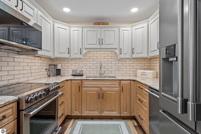 kitchen featuring white cabinets, stainless steel appliances, light stone countertops, and sink