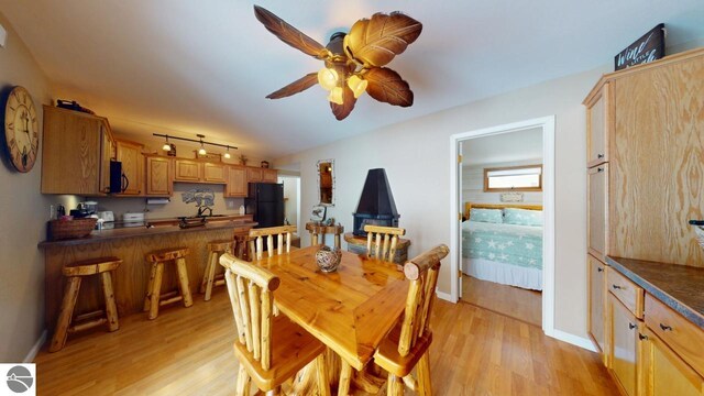 dining space with baseboards, ceiling fan, light wood-style floors, and rail lighting