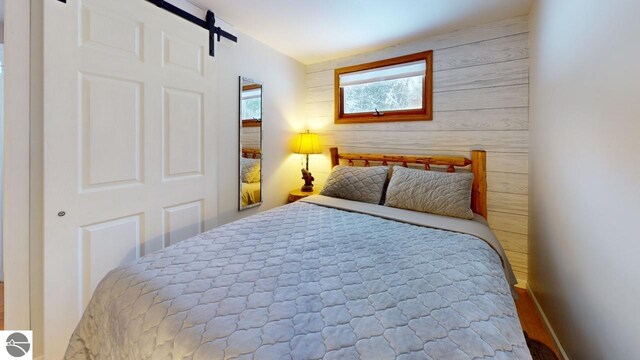 bedroom featuring a barn door and wooden walls