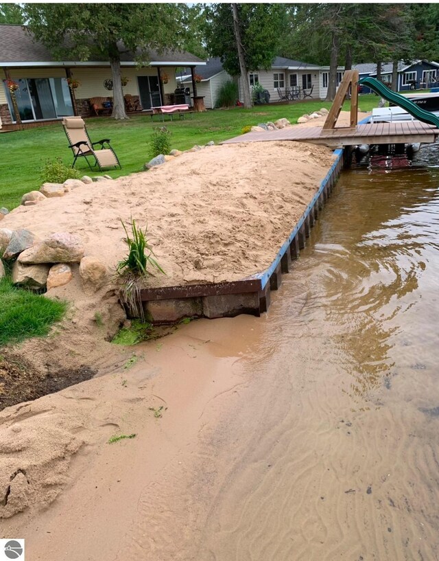 exterior space featuring a water view, a boat dock, and a lawn