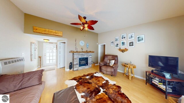 living room with vaulted ceiling, a fireplace, wood finished floors, baseboards, and ceiling fan