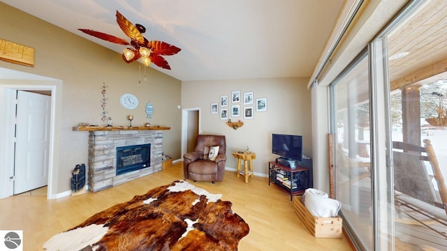 living area featuring a fireplace, wood finished floors, vaulted ceiling, and ceiling fan