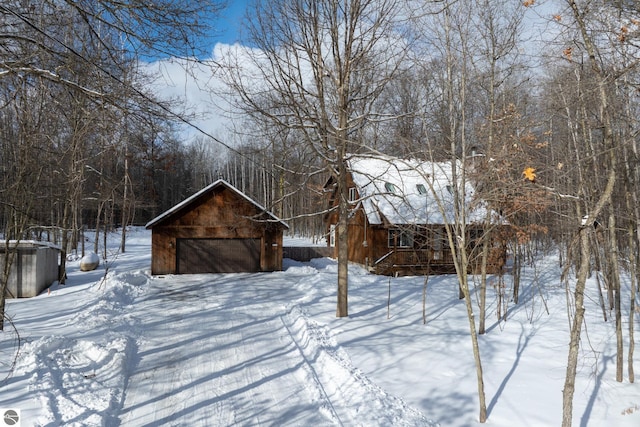 snowy yard featuring an outbuilding and a garage