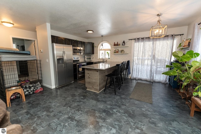 kitchen featuring appliances with stainless steel finishes, a breakfast bar area, decorative light fixtures, sink, and kitchen peninsula