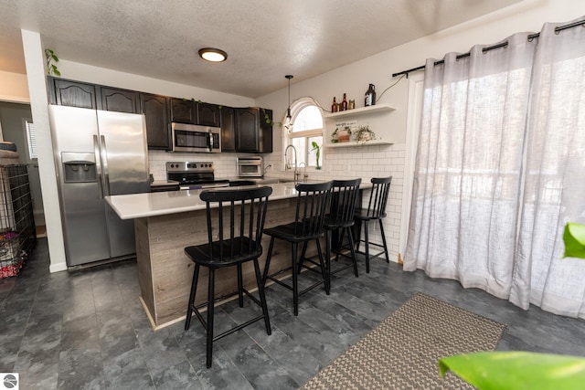 kitchen with kitchen peninsula, appliances with stainless steel finishes, hanging light fixtures, and a breakfast bar