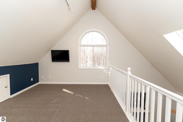 additional living space with dark carpet and vaulted ceiling with skylight