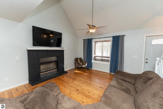 living room featuring ceiling fan, vaulted ceiling, a brick fireplace, and hardwood / wood-style floors