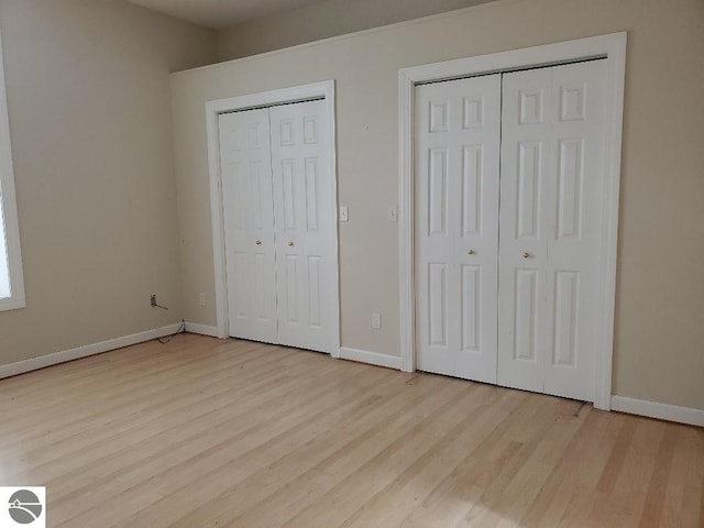 unfurnished bedroom with multiple closets and light hardwood / wood-style floors