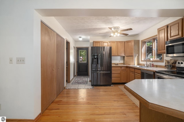 kitchen with stainless steel appliances, a textured ceiling, ceiling fan, light hardwood / wood-style floors, and sink