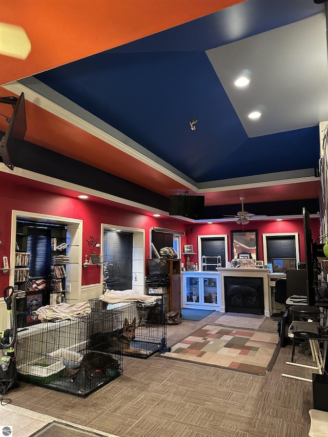 carpeted living room featuring ceiling fan, exterior fireplace, and a tray ceiling