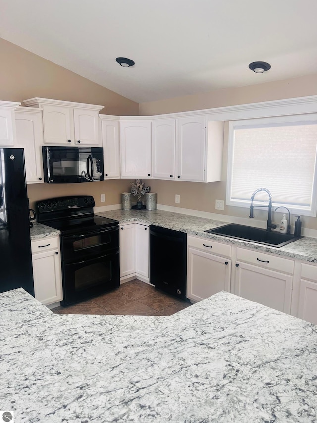 kitchen featuring tile patterned flooring, black appliances, lofted ceiling, sink, and white cabinetry