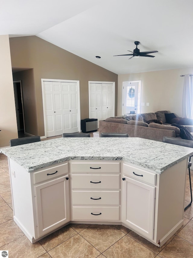 kitchen with white cabinets, light stone countertops, and a center island