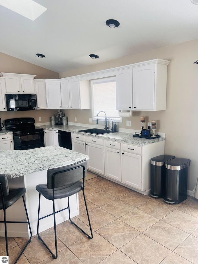 kitchen featuring a kitchen breakfast bar, white cabinets, black appliances, light tile patterned flooring, and sink