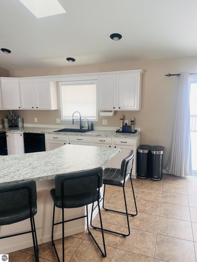 kitchen featuring white cabinets, a kitchen bar, sink, and light tile patterned flooring